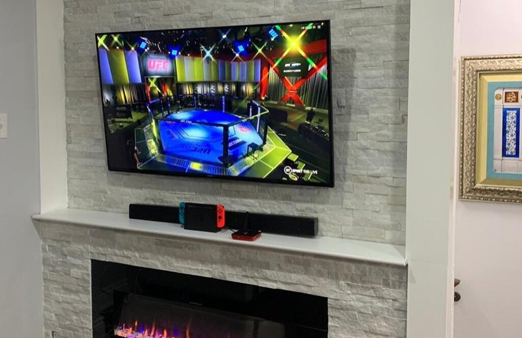 Wall-mounted television set above a stone-faced fireplace