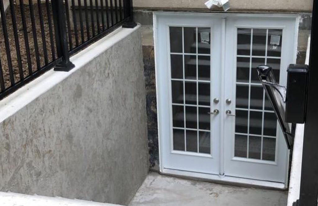 Separate basement entrance with double doors and metal railings